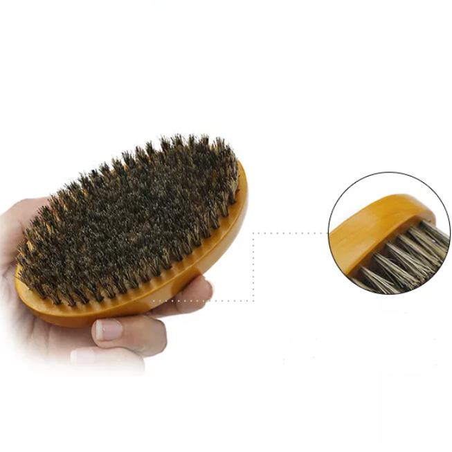 Boar's hair beard brush in a man's hand to show size