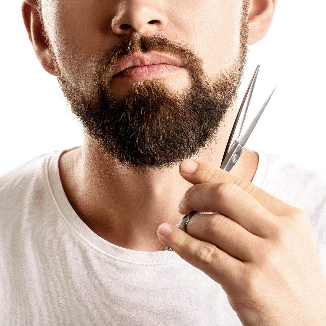 Man with short beard trimming his beard with scissors