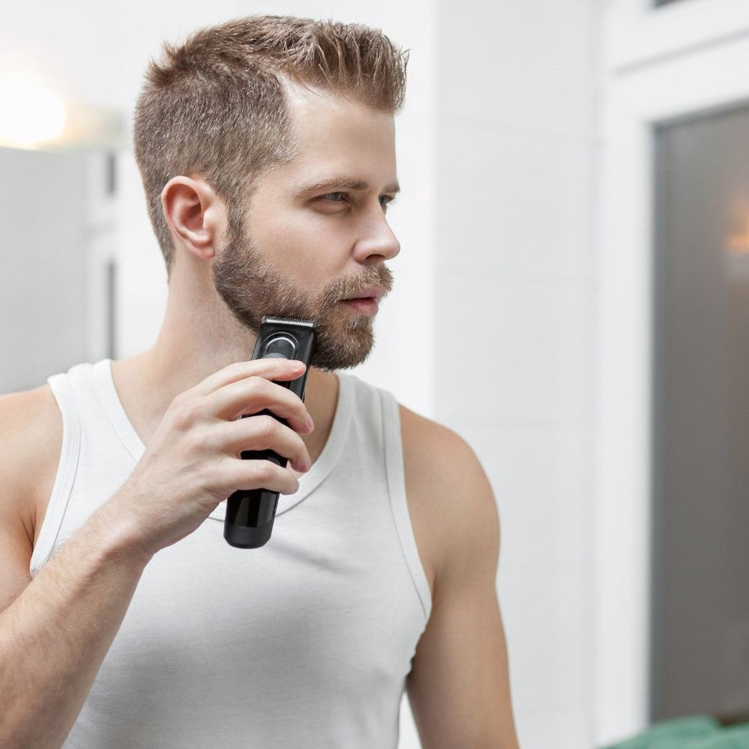 Man trimming a beard with a trimmer in the bathroom