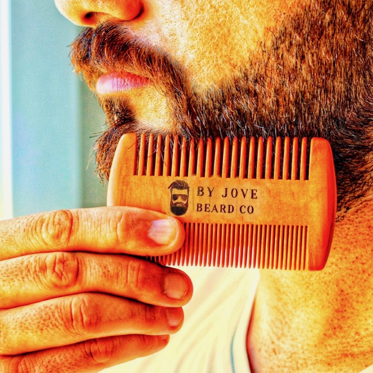 Man combing beard with sandalwood beard comb